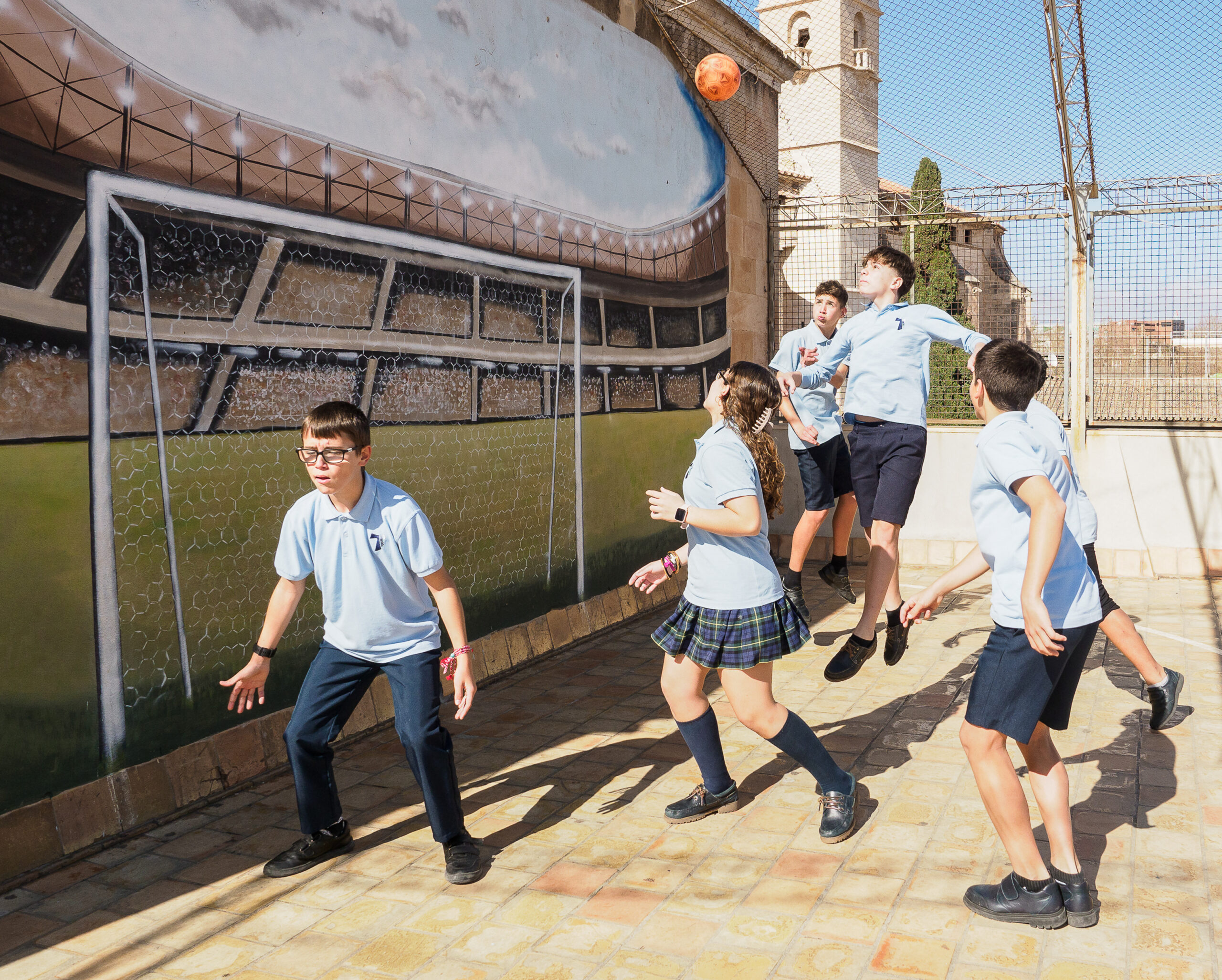 Niños y niñas jugando en el patio a la pelota